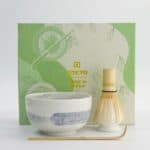 Japanse theeset met groene en witte theekop, theelicht en theelepel, op een witte achtergrond.