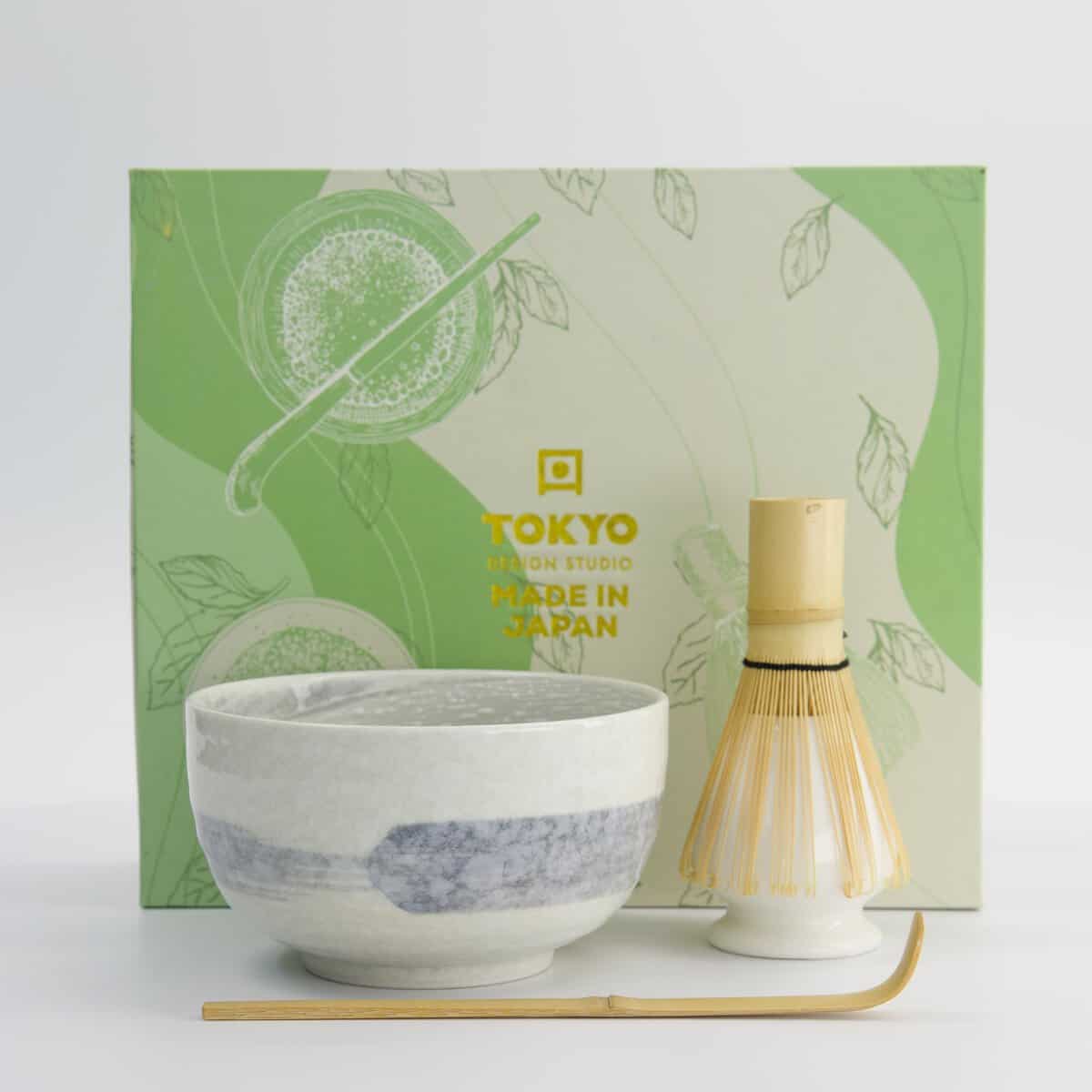 Japanse theeset met groene en witte theekop, theelicht en theelepel, op een witte achtergrond.