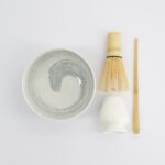 Traditionele Japanse theeset met bamboe whisk, kom en lepel voor matcha thee, minimalistisch design op witte achtergrond.