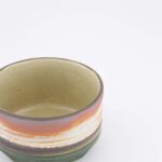 Handgemaakte keramische kom met aardetinten en glanzende afwerking, perfect voor servies en decoratie.