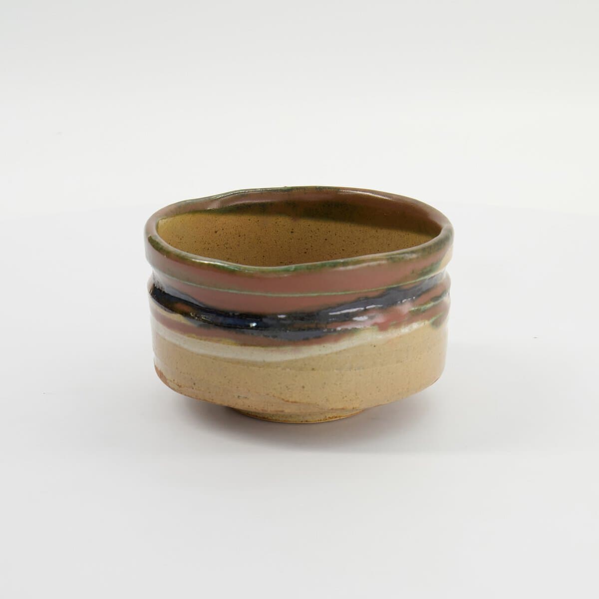 Handgemaakte keramische kom met aardetinten en kleurrijke strepen, perfect voor servies en decoratie.