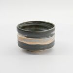Handgemaakte keramische kom met aardse kleuren en eenvoudige design, perfect voor servies en decoratie.