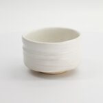 Witte keramische kom met eenvoudige, strakke lijnen, perfect voor servies of decoratie, op een witte achtergrond.