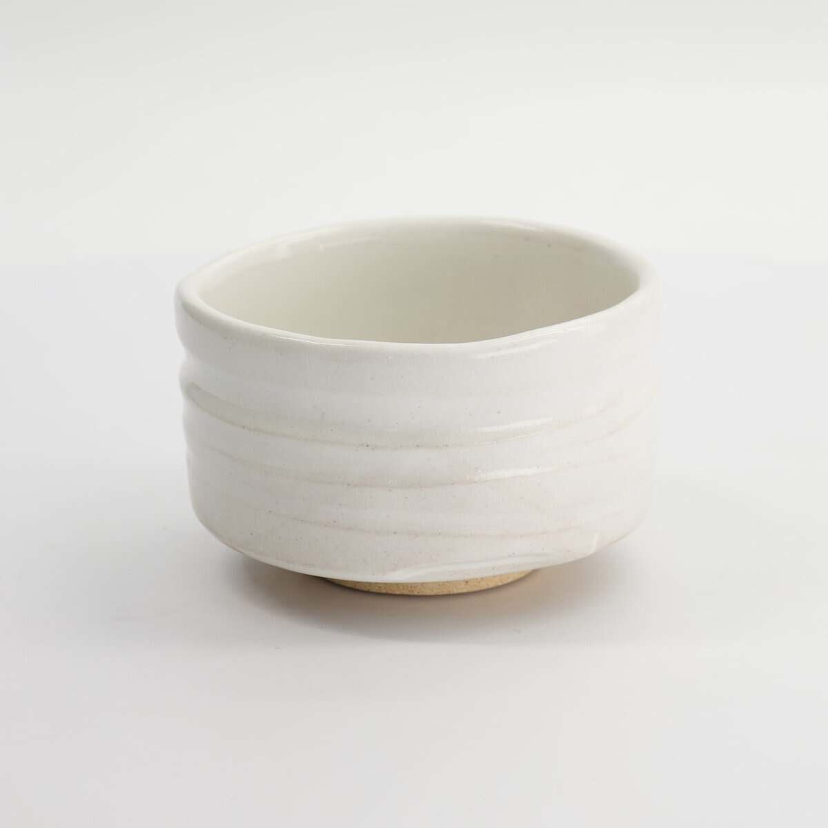 Witte keramische kom met eenvoudige, strakke lijnen, perfect voor servies of decoratie, op een witte achtergrond.