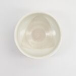 Witte keramische kom met een subtiele spiraalpatroon, geschikt voor koken en serveren, op een witte achtergrond.