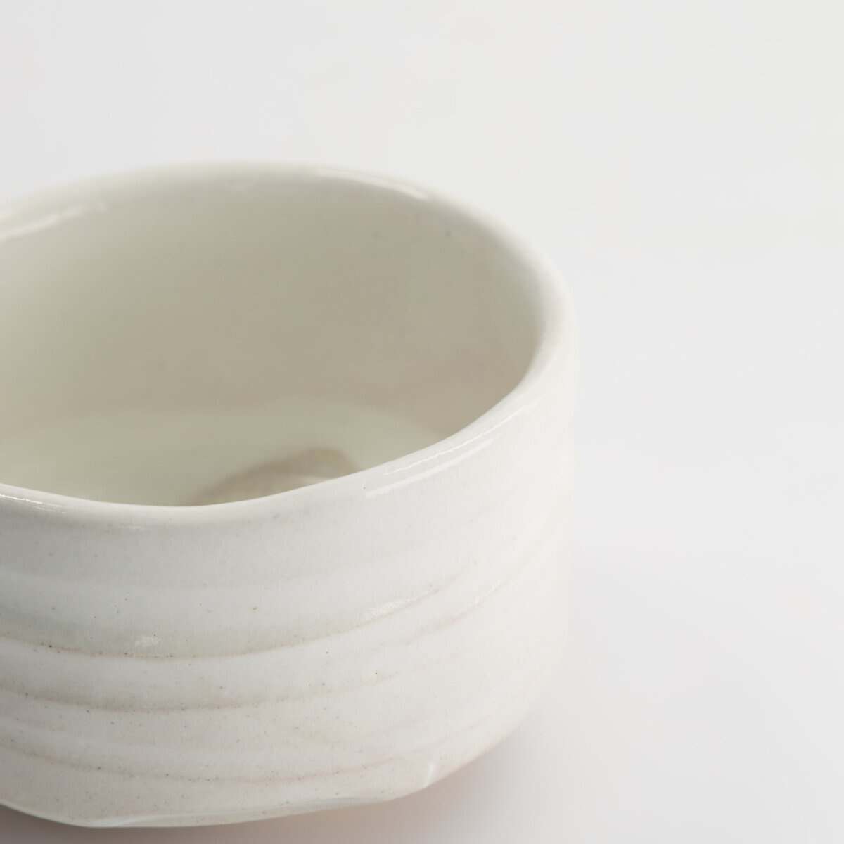 Witte keramische kom met eenvoudige, strakke ontwerp op een witte achtergrond, perfect voor keuken- en serveeraccessoires.